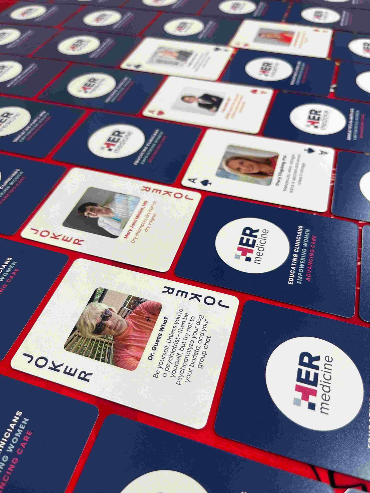 Playing cards with 'Just 1 More' logo on a branded card holder.
